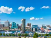 Baltimore's inner harbor under a bright blue sky with fluffy white clourd