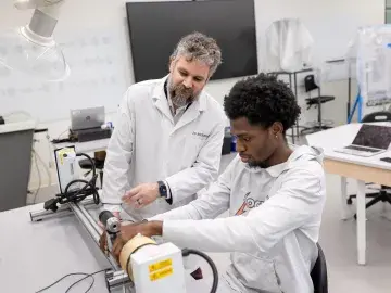 Two researchers in lab coats working with electronics equipment in a bright lab