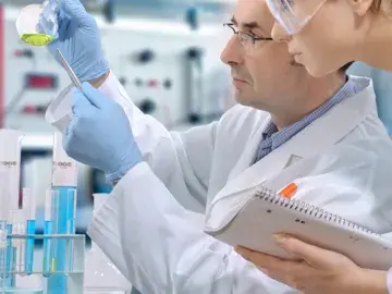 Two scientist looking at a beaker. 