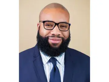 Eben Smith with glasses and full beard in suit and tie.