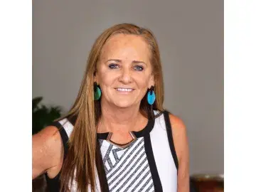 Kathie Callahan Brady in striped dress against gray background.