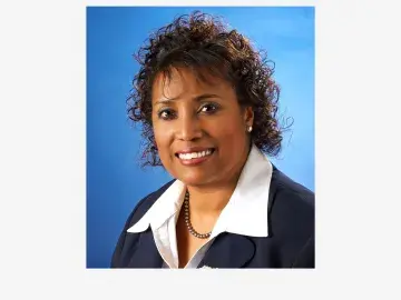 Linda Cureton, PhD in a dark blazer and white collared shirt against a blue backdrop.