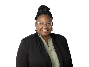 Rajaniece Thompson smiling in glasses, black blazer, on white background.