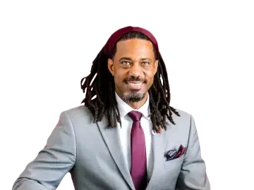 Kory Bailey in a light gray suit and burgundy tie, seated on a black background