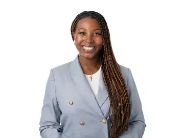 Tami Yoloye smiling with long braids in a light blue blazer on white background
