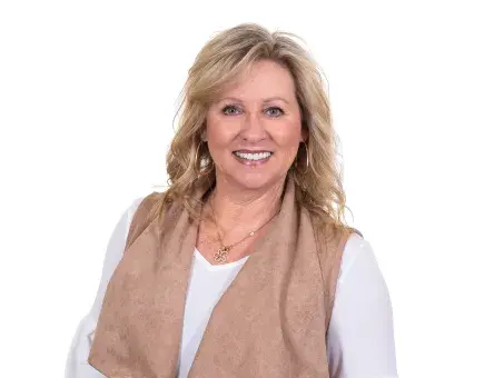 Diana Smith in white top and tan vest against a white background.