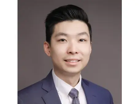 Chung Hei Sing in a suit and tie against a gray background