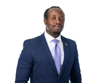 Omoregie Okhomina in a navy suit and purple tie against a white background